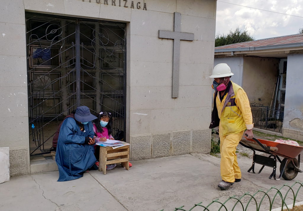 Jeanete Alanoca who works at a cemetery helps her daughter Neydy with their school tasks at the Cementerio General cemetery in La Paz