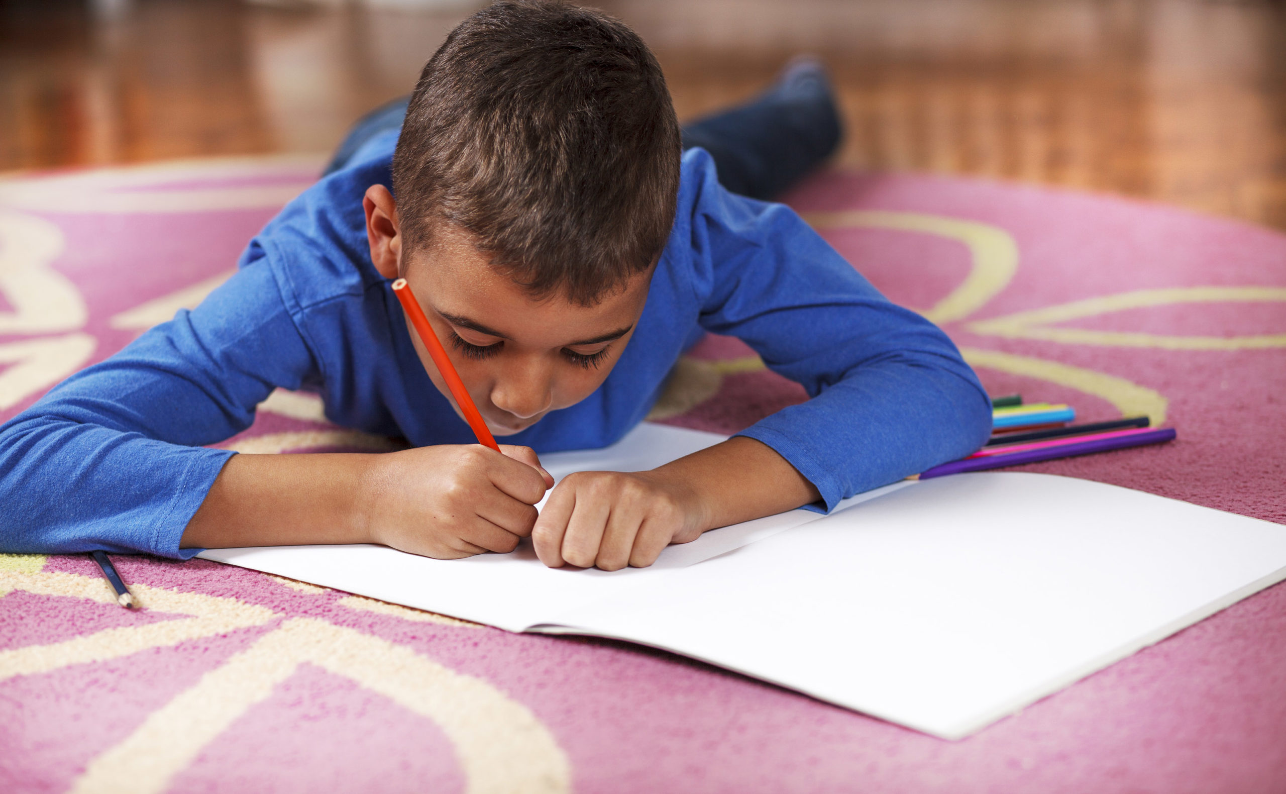 boy drawing on paper with crayon.