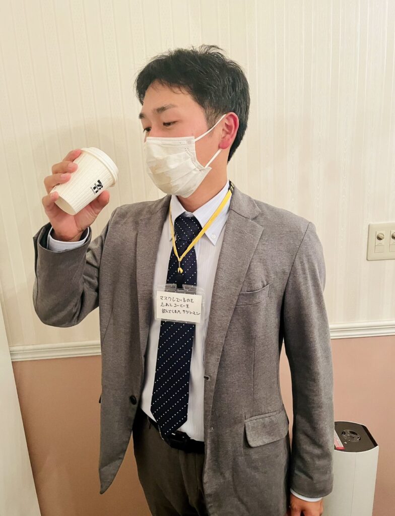 A person who forgot to take off his mask before taking a sip of coffee